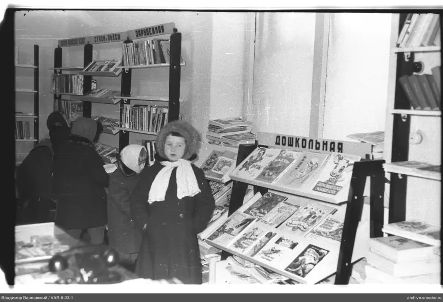 Девочка у книжных полок в библиотеке
