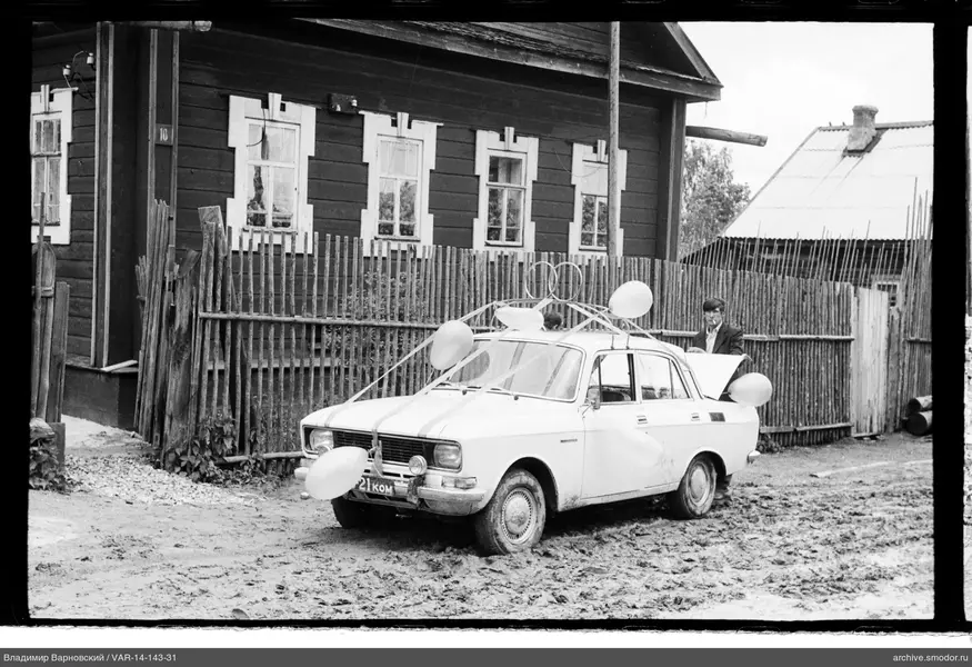 Украшенная машина и мужчина у деревянного дома