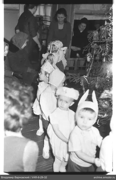 Kinder neben geschmücktem Weihnachtsbaum