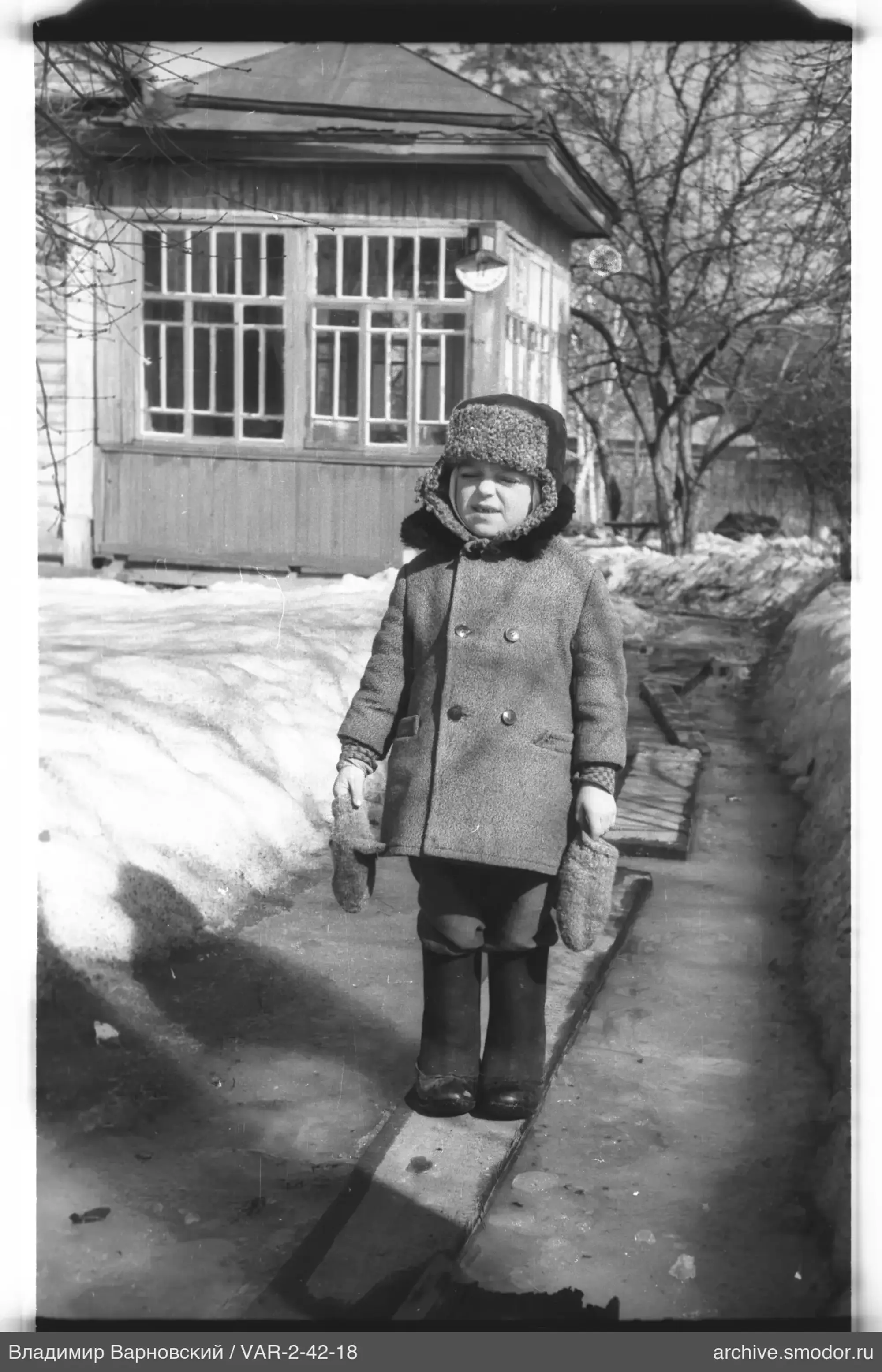 Kind auf Holzbrett im Schnee