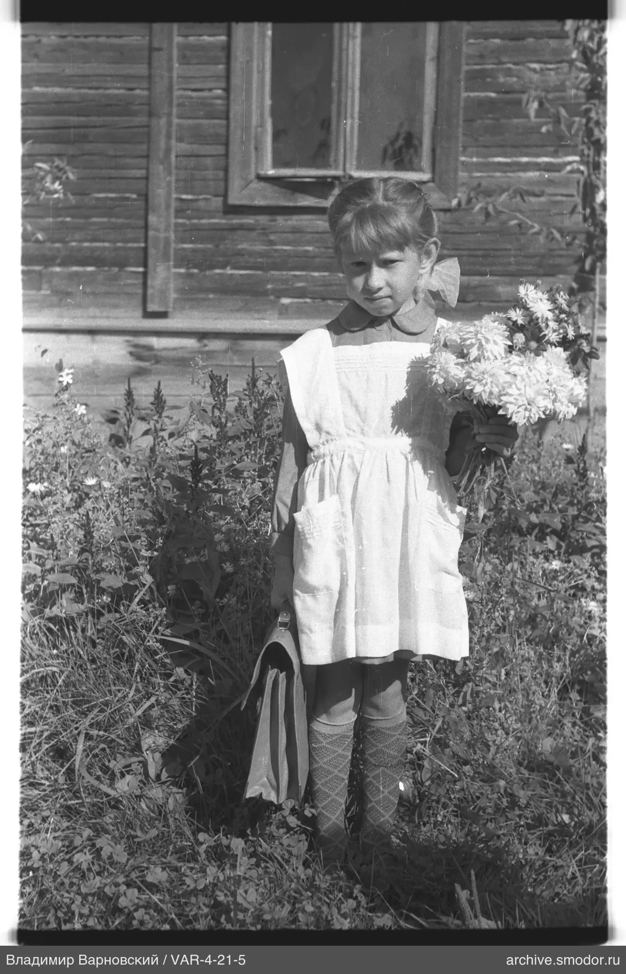 Mädchen mit Blumenstrauß vor einem Holzhaus