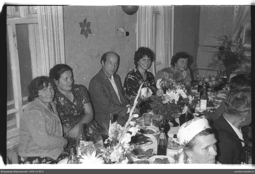 Gruppe am Tisch mit Blumen und Geschirr
