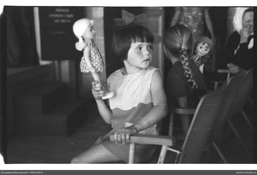 Mädchen mit Puppen und Frau im Kopftuch