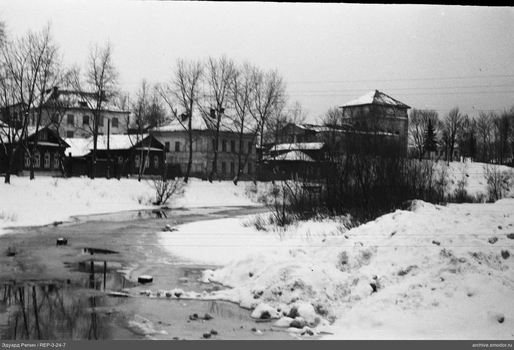 Landschaft mit Fluss und Gebäuden im Winter