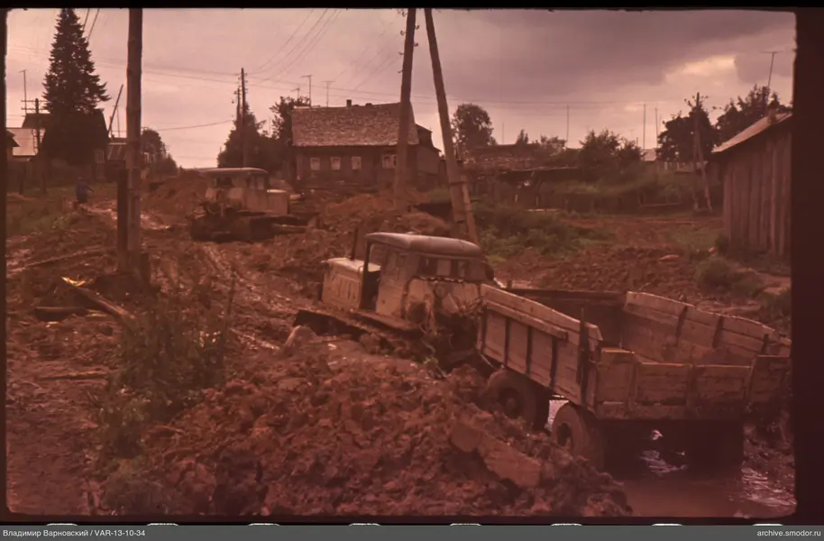 Tractors on a rural street with houses and trees