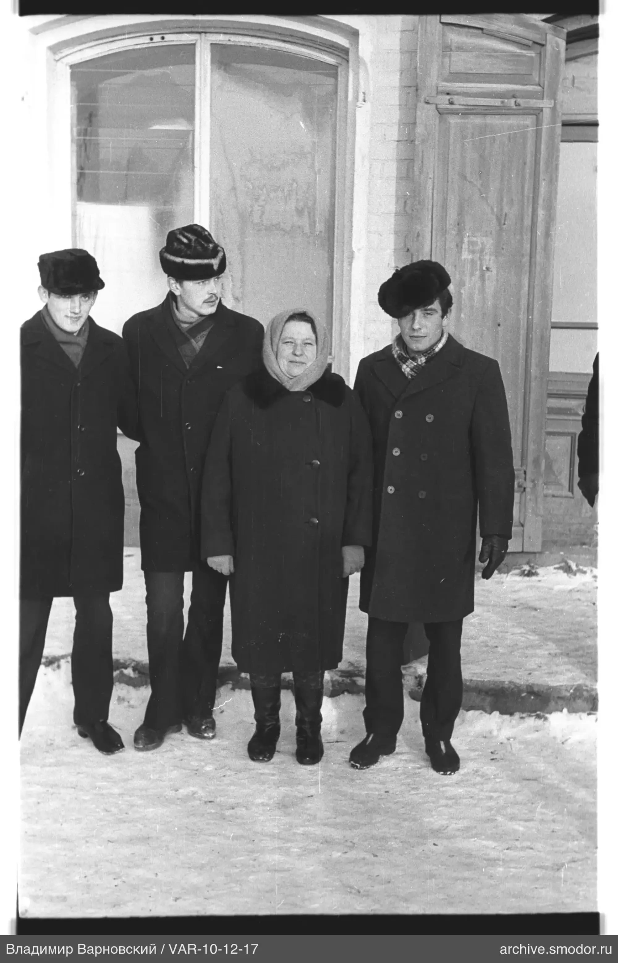 Gruppe von Menschen im Schnee vor einem Ziegelgebäude