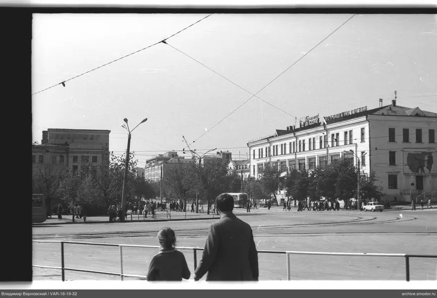 Man and child by fence on city square