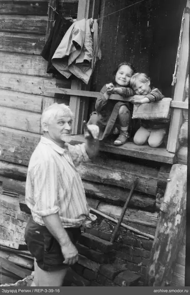 Mann mit erhobener Hand am Holzhaus