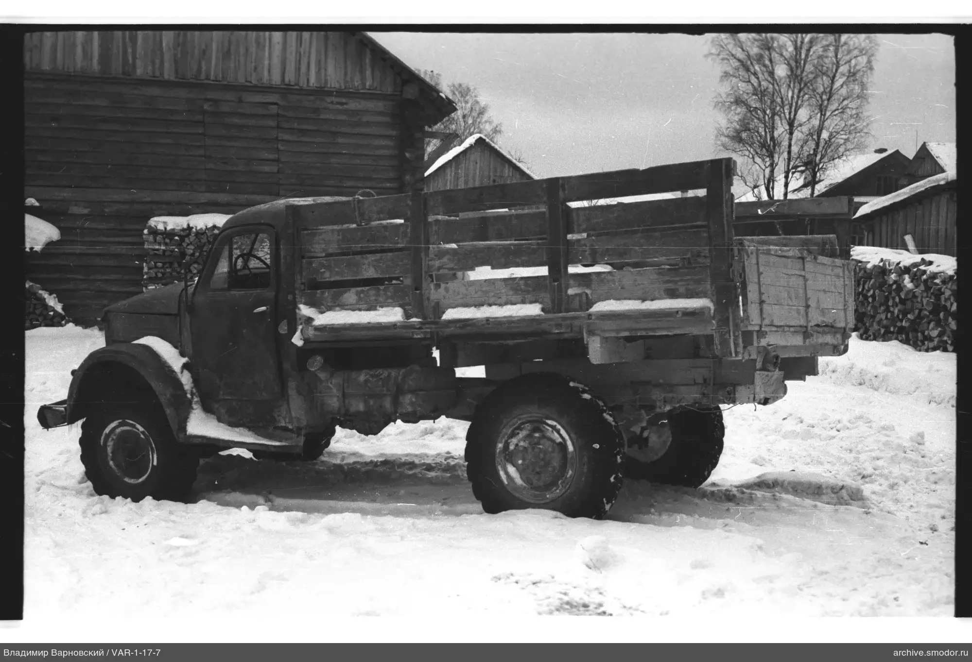 Lastwagen im Schnee neben Holzgebäude