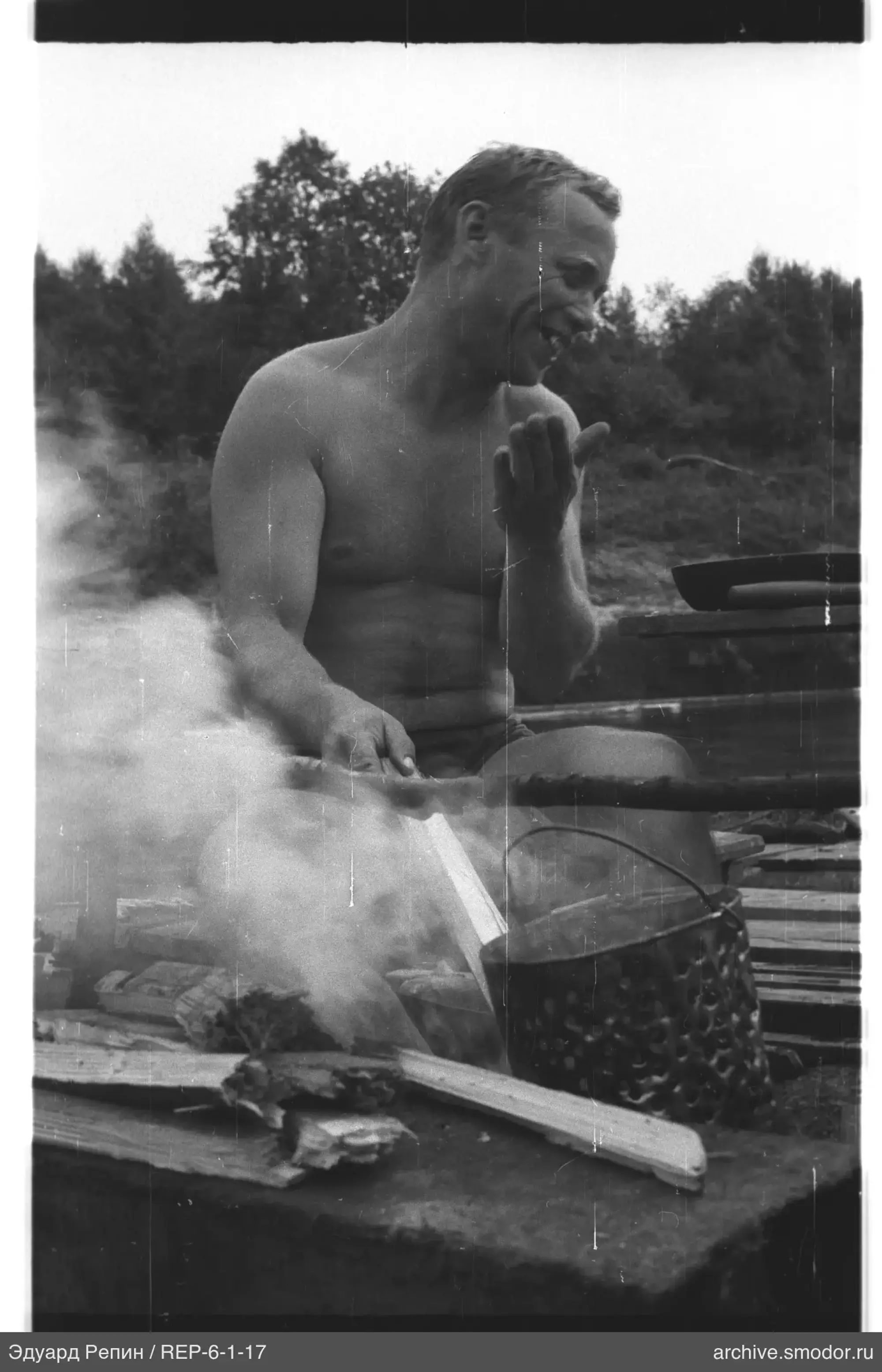 Man with container near campfire