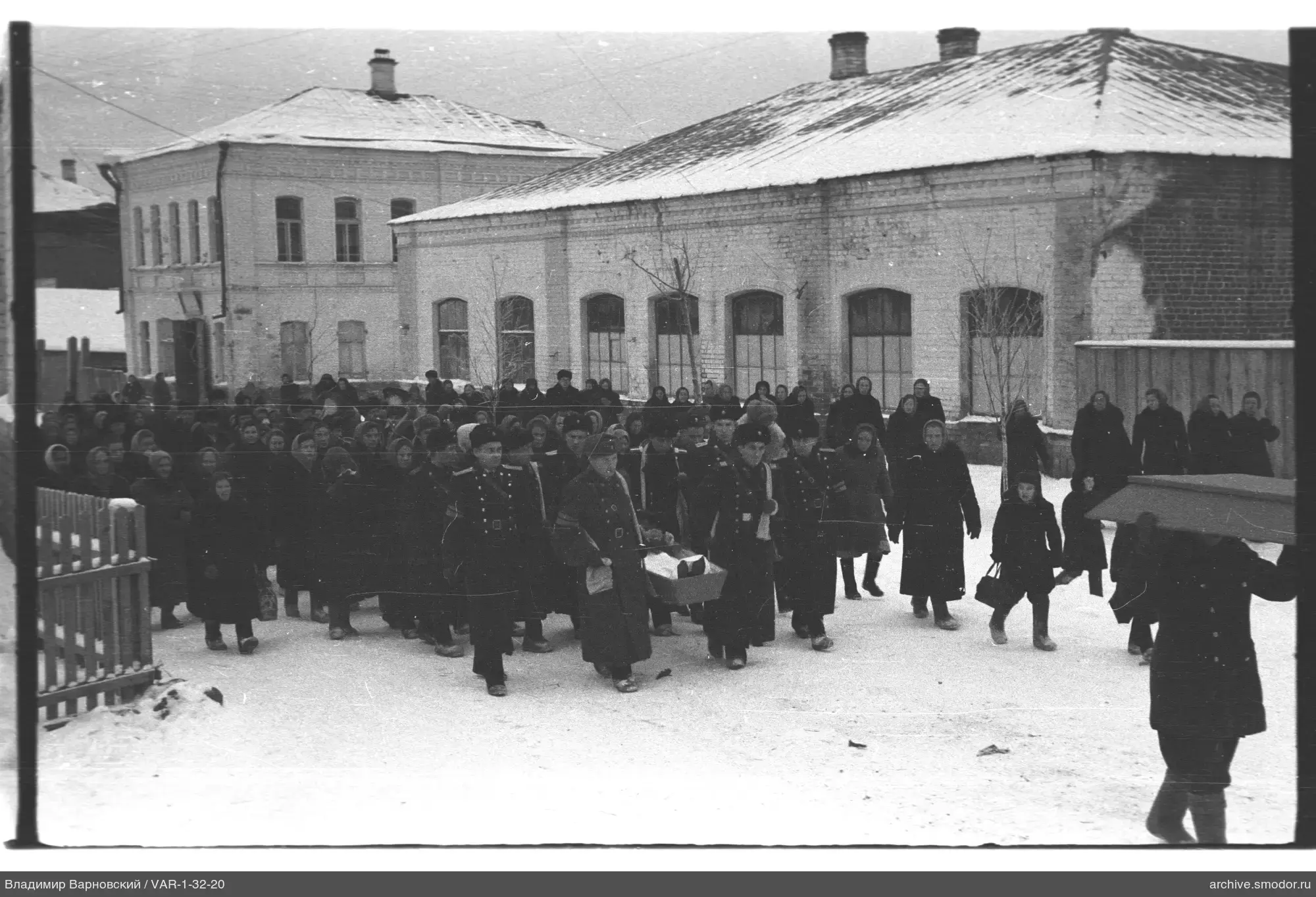 Группа людей на снежной улице с носилками и гробом