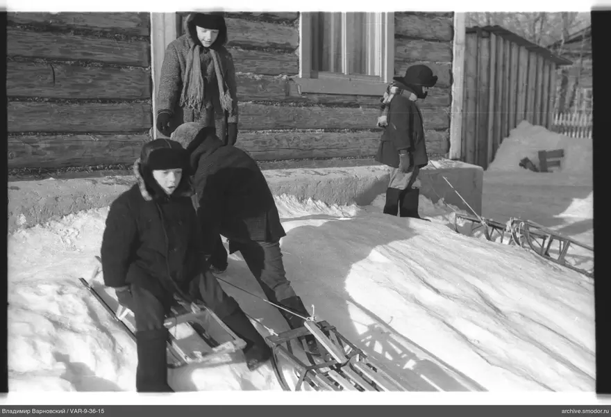 Kinder im Schnee bei einem Holzhaus
