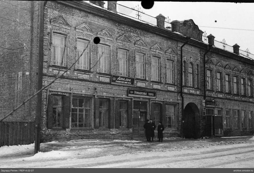 Здание с вывесками и тремя людьми на снегу