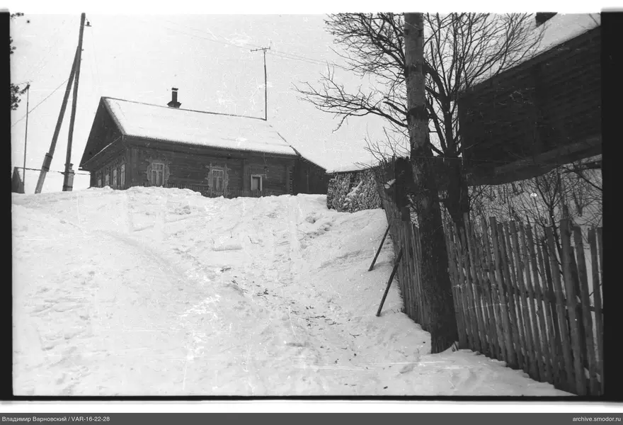 Holzhaus mit Schnee und Spuren am Hang