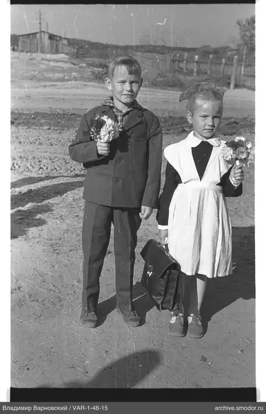 Porträt von zwei Kindern mit Blumen und Schultasche