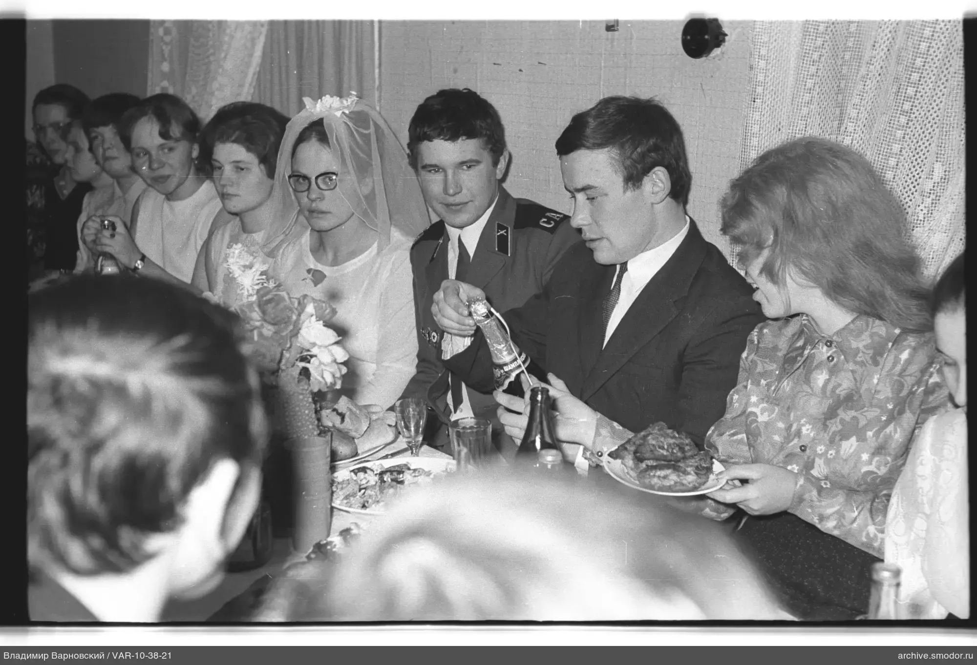 Gruppe am Tisch mit Frau im Hochzeitskleid