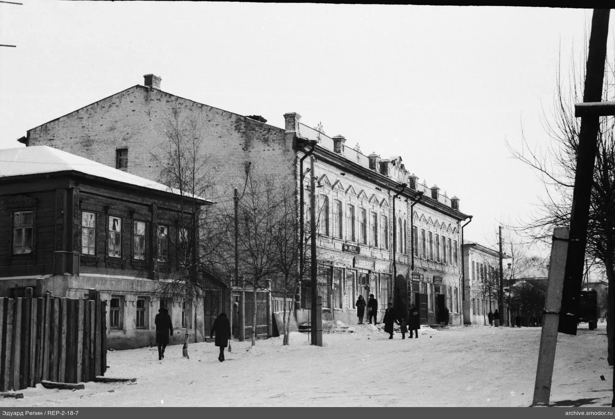 Verschneite Straße mit Gebäuden und Menschen