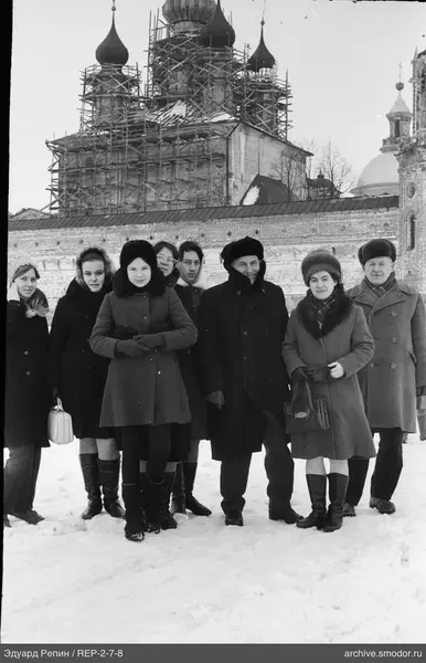 Gruppe von Menschen vor altem Gebäude im Schnee