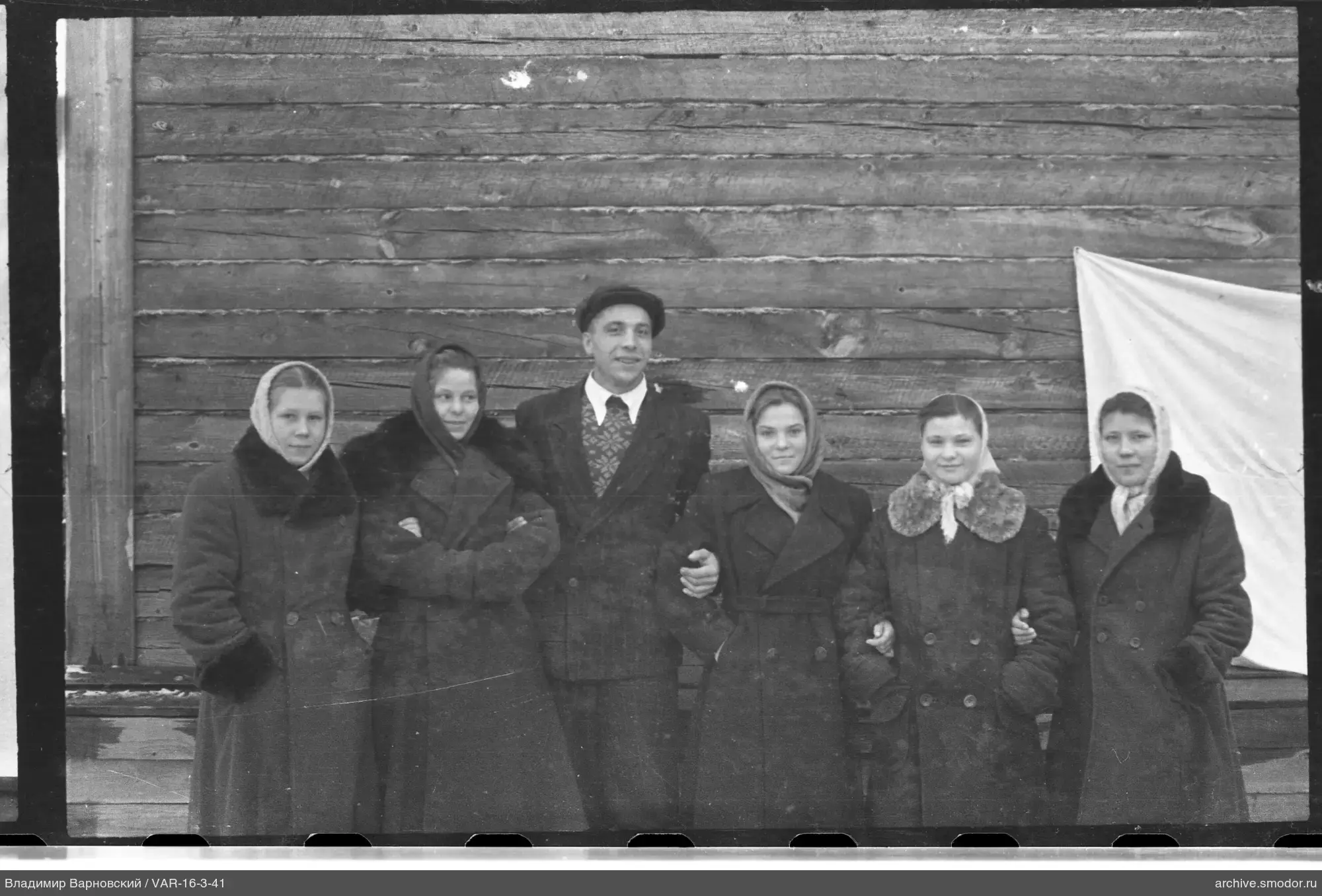 Группа людей у деревянной стены