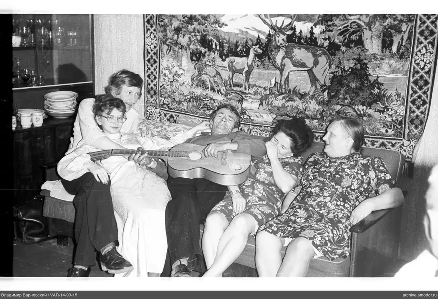 Group sitting on sofa with guitar and carpet