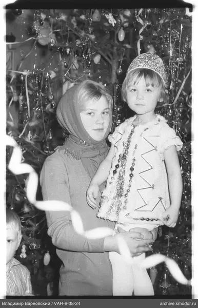 Frau mit Mädchen vor geschmücktem Weihnachtsbaum