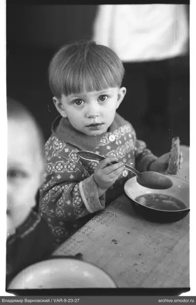 Child with spoon and bread at table