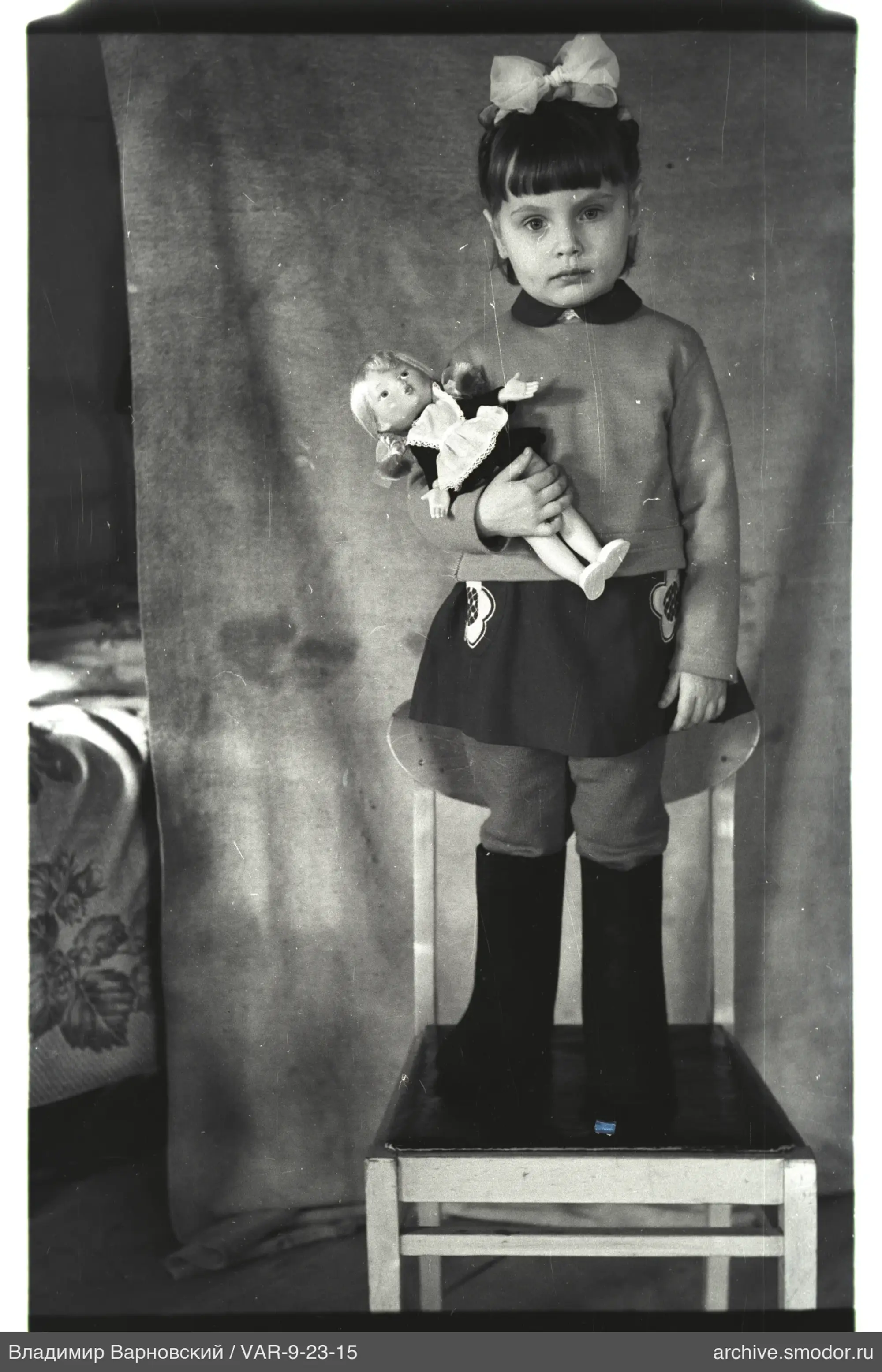 Mädchen mit Puppe auf Stuhl