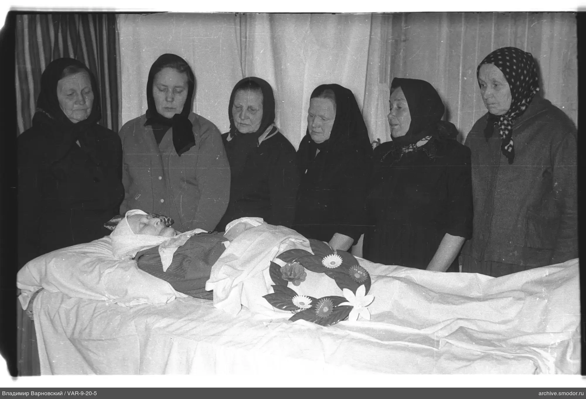 Шесть женщин у тела с венком и повязкой