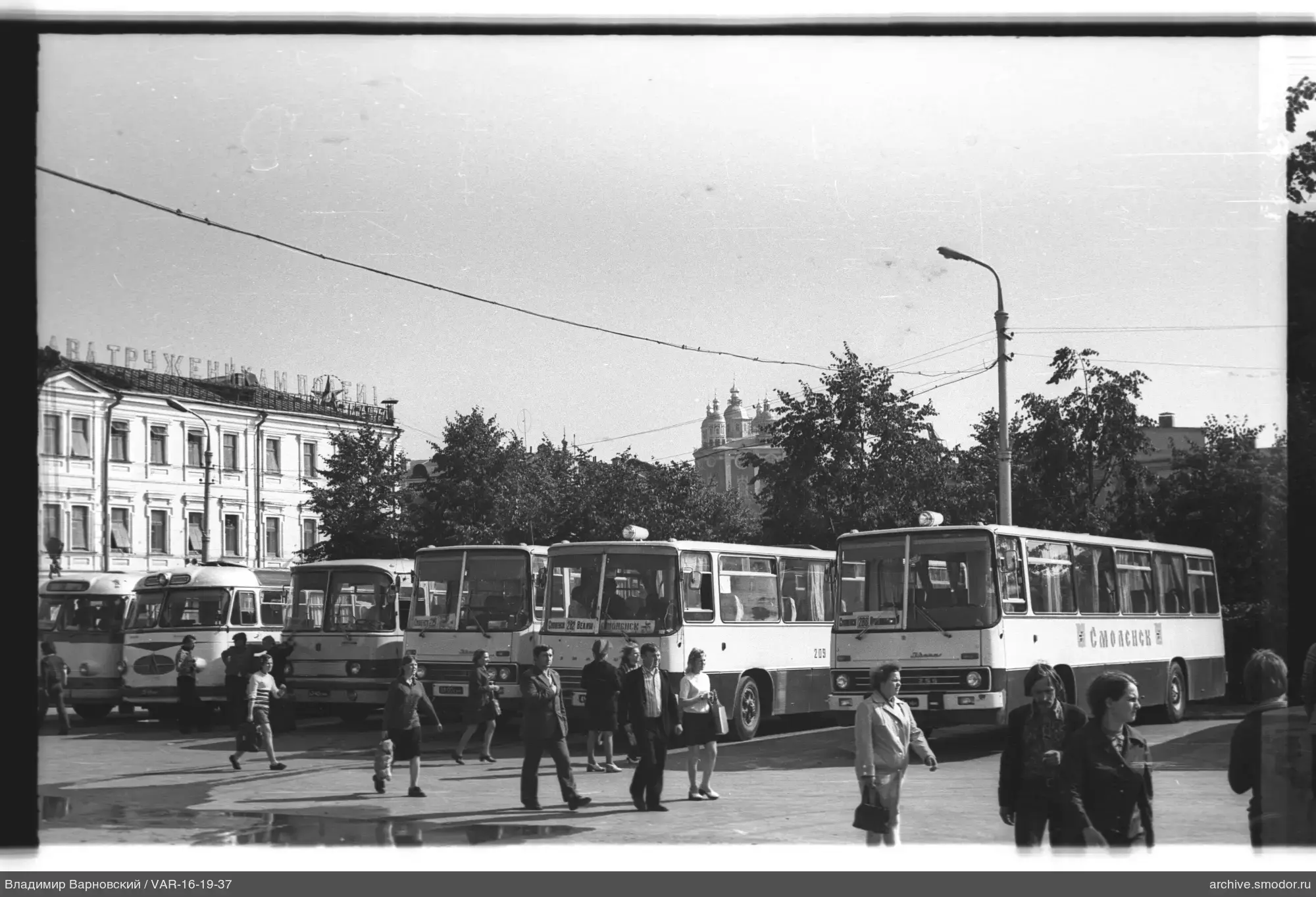 Menschen auf Platz mit Bussen und Gebäude