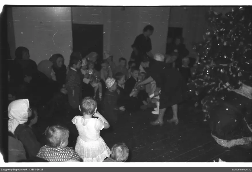 Gruppe von Kindern und Erwachsenen bei Weihnachtsbaum