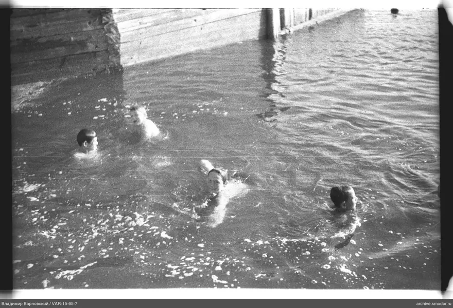 Jungen schwimmen bei einem hölzernen Steg
