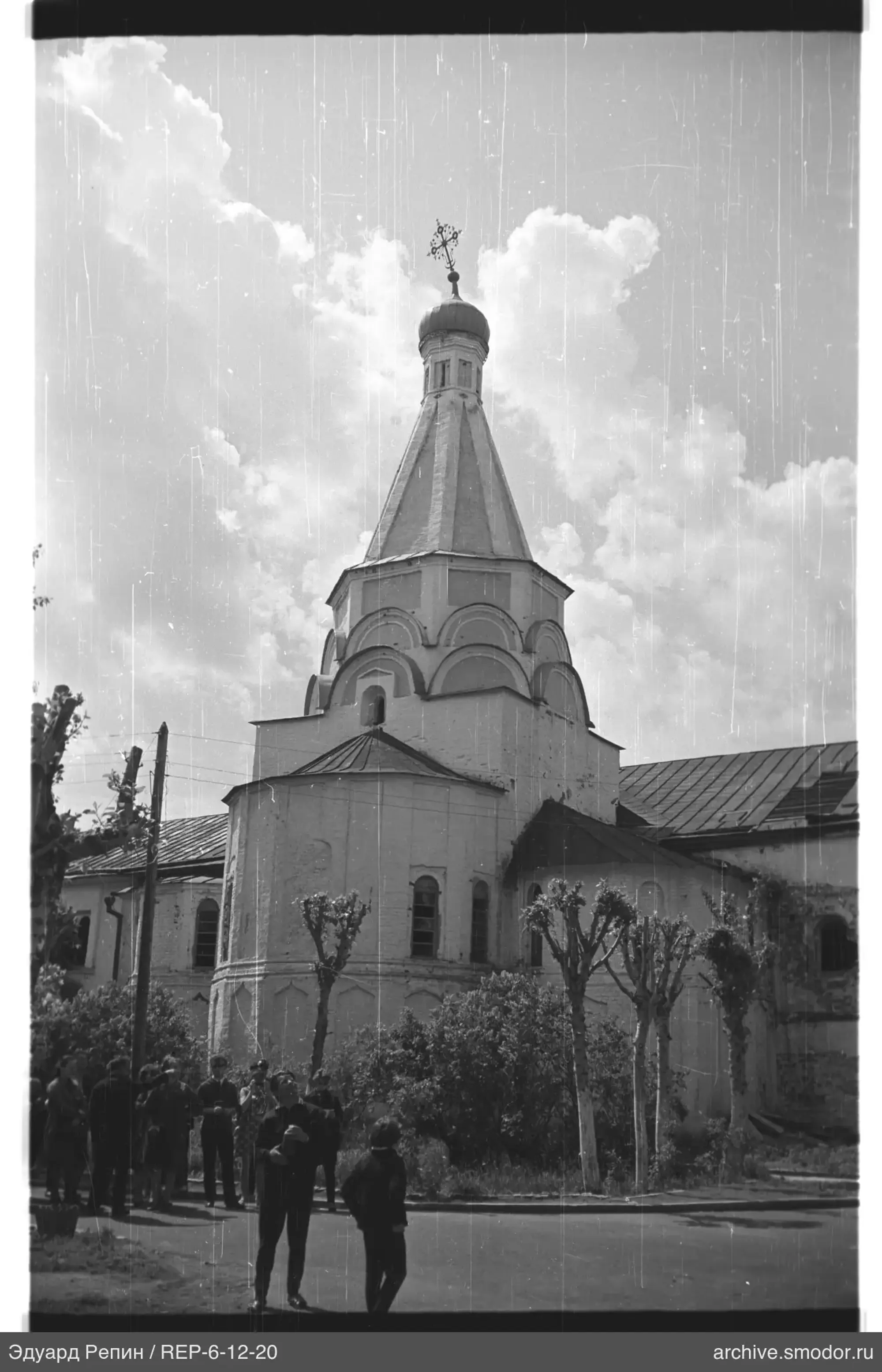 Группа людей у здания с башней и крестом