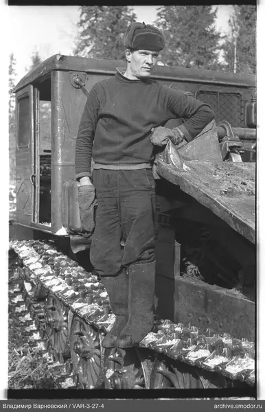 Man with tracked tractor against trees