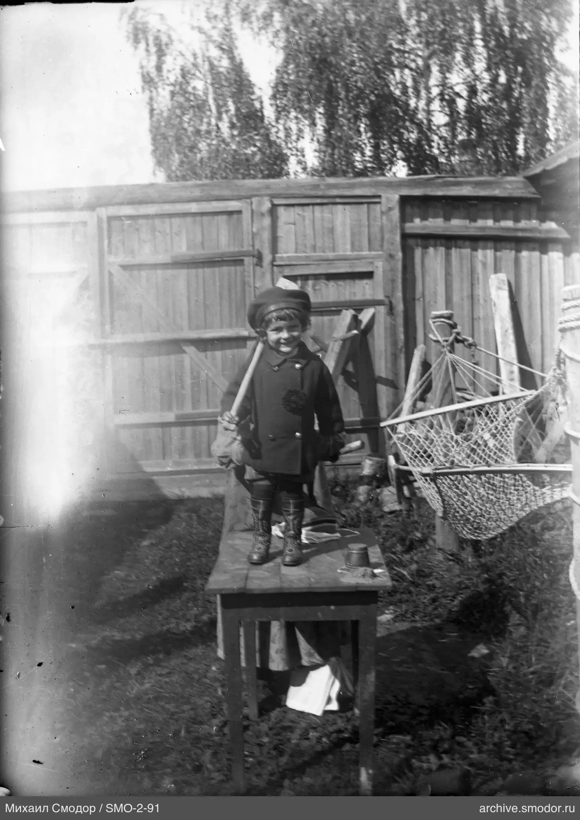 Ребёнок с палкой у деревянного забора