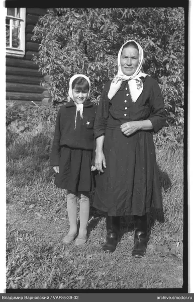Frau und Mädchen vor Haus auf Gras
