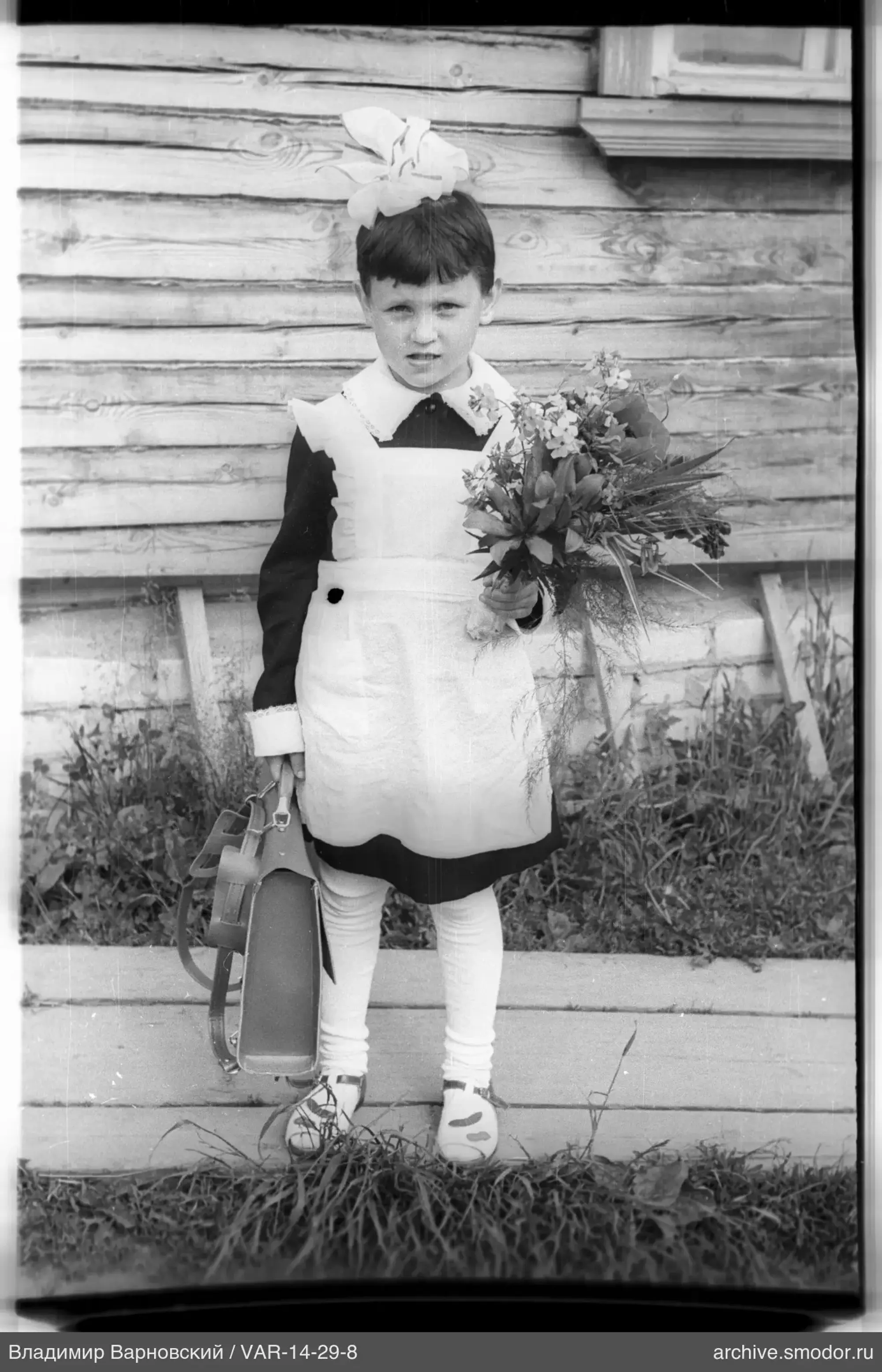 Ganzkörperporträt eines Mädchens mit Blumen und Schultasche