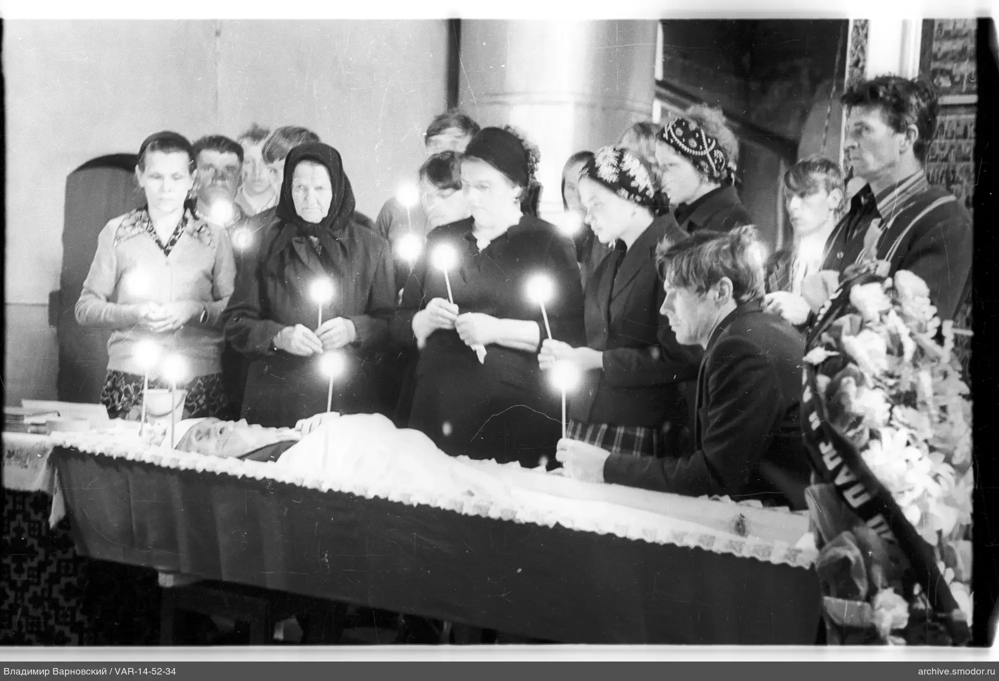 Group around an open coffin with a man's body