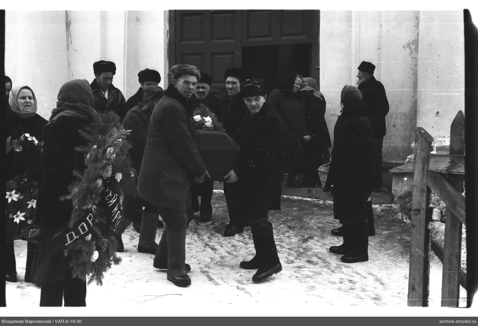 Люди у входа в здание с гробом и венком