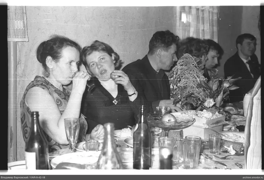 Group sitting at a table with dishes and floral arrangement