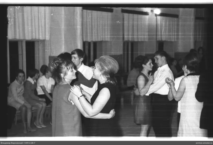 People dancing in a room with curtained windows