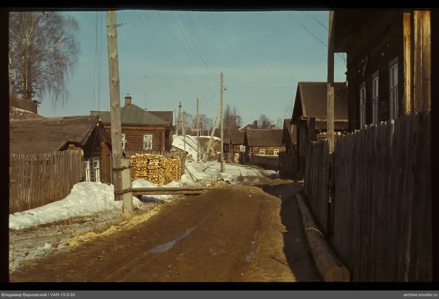 Dirt road between wooden houses with electric wires