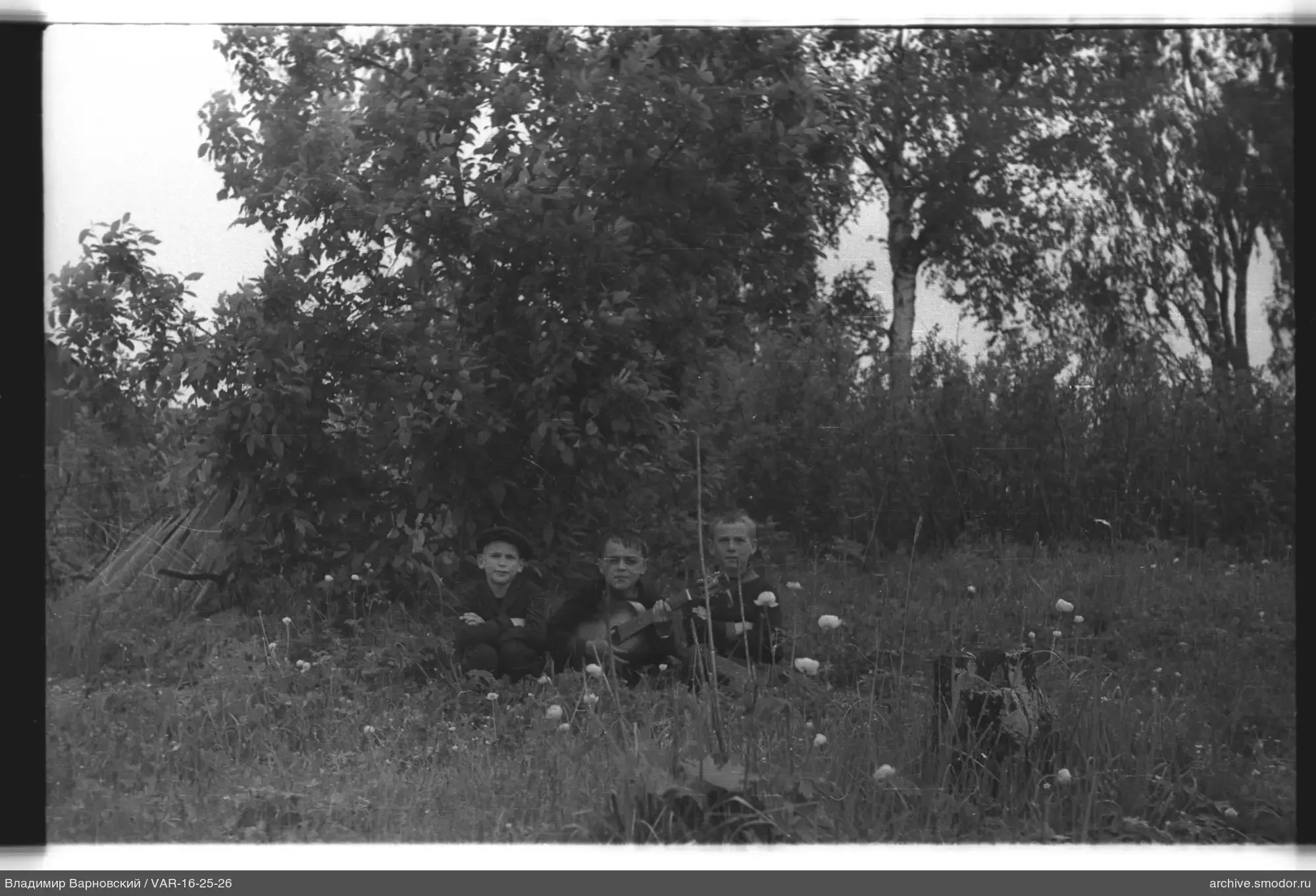 Drei Jungen mit Gitarre im Gras