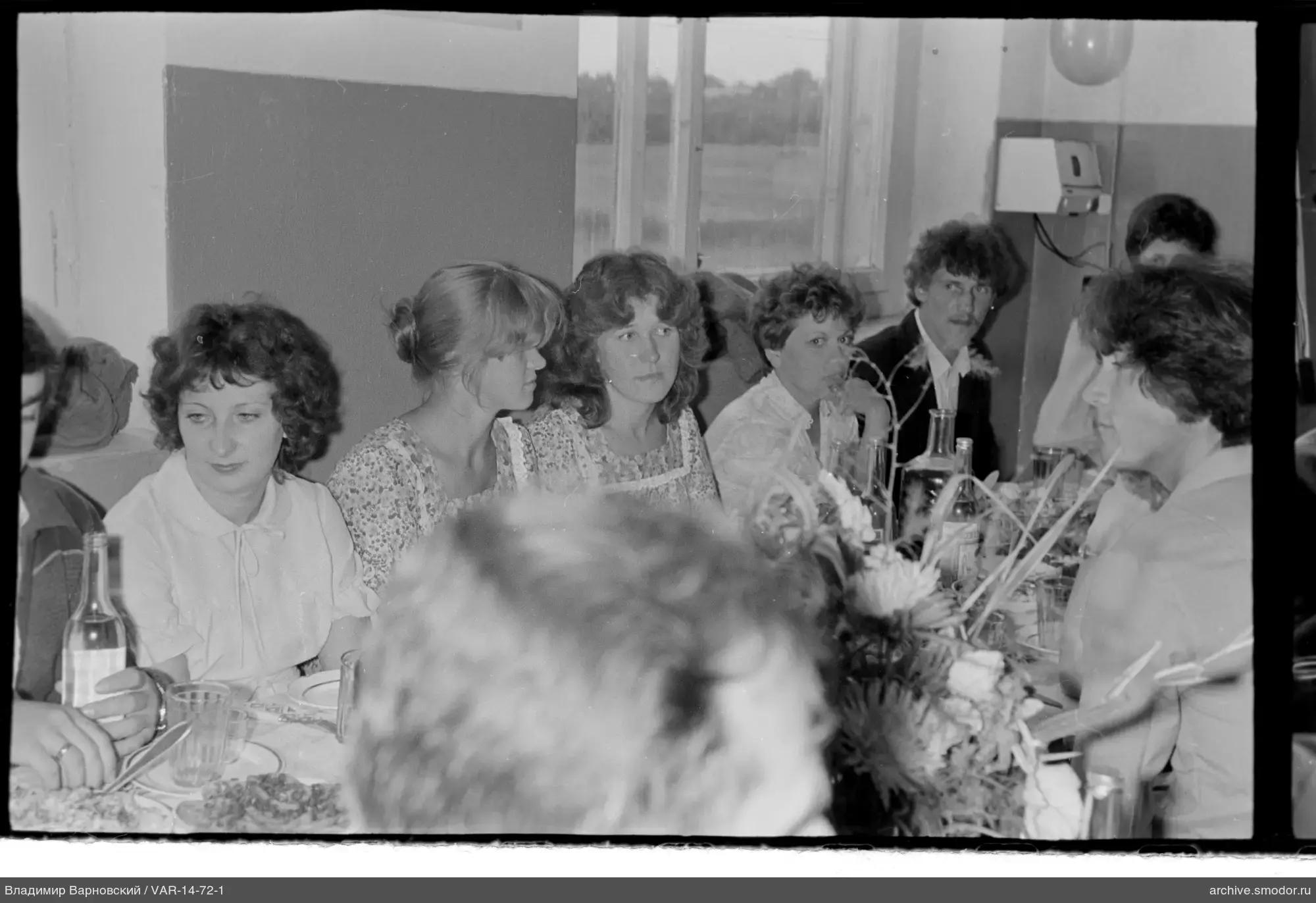 Group of men and women at a table with dishes and flowers