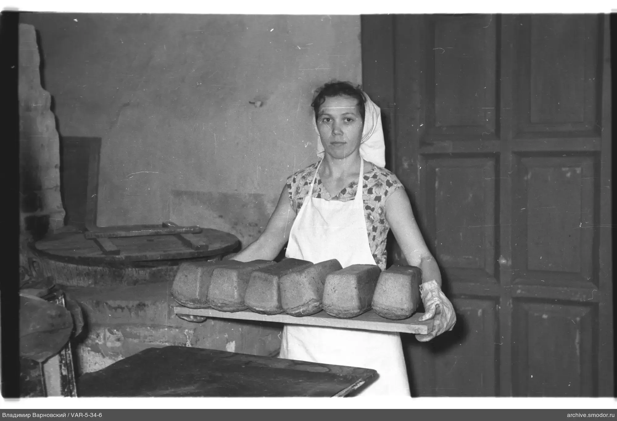 Frau mit Brot vor dem Ofen