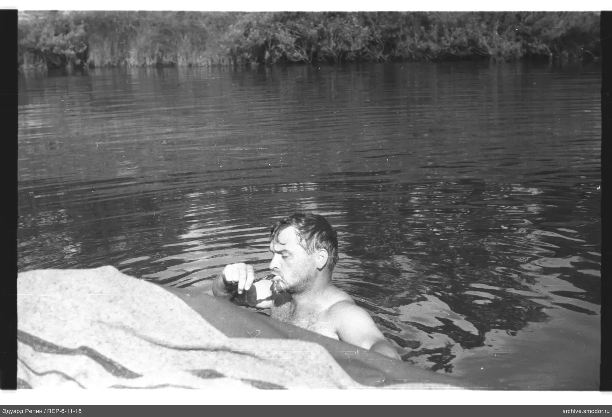 Мужчина пьёт у берега в воде