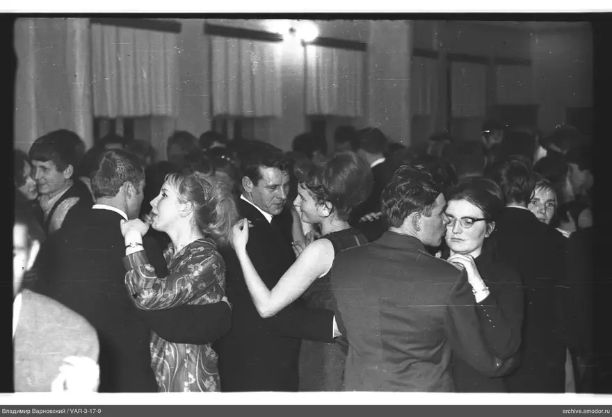 Dancing couples in a room with curtained windows