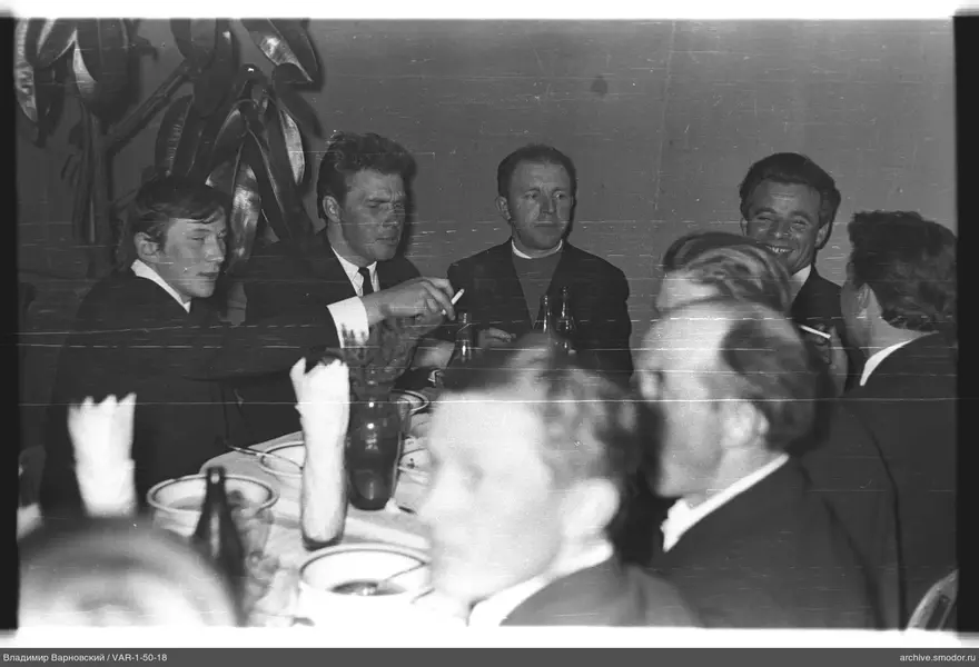 Men at a table with dishes and cigarettes