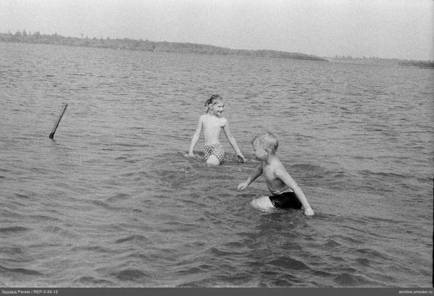 Kinder im Wasser am Ufer mit Bäumen