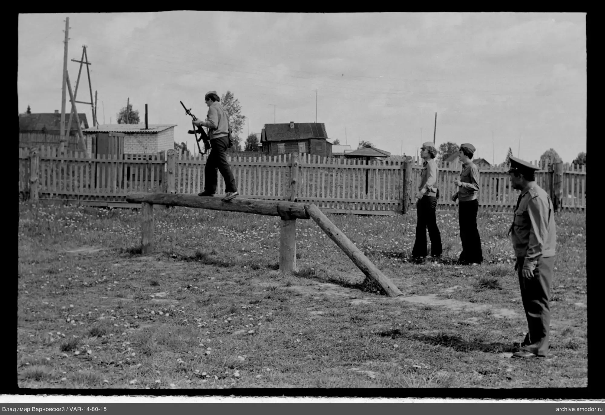Mann mit Waffe auf Baumstamm