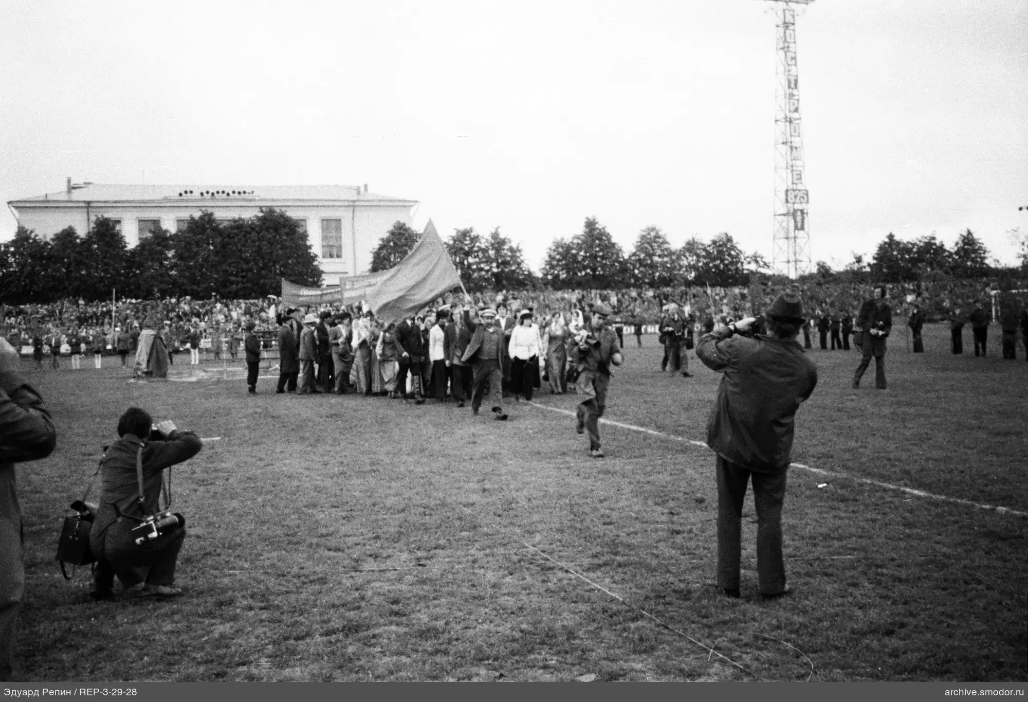Группа людей с флагом и фотографы на поле